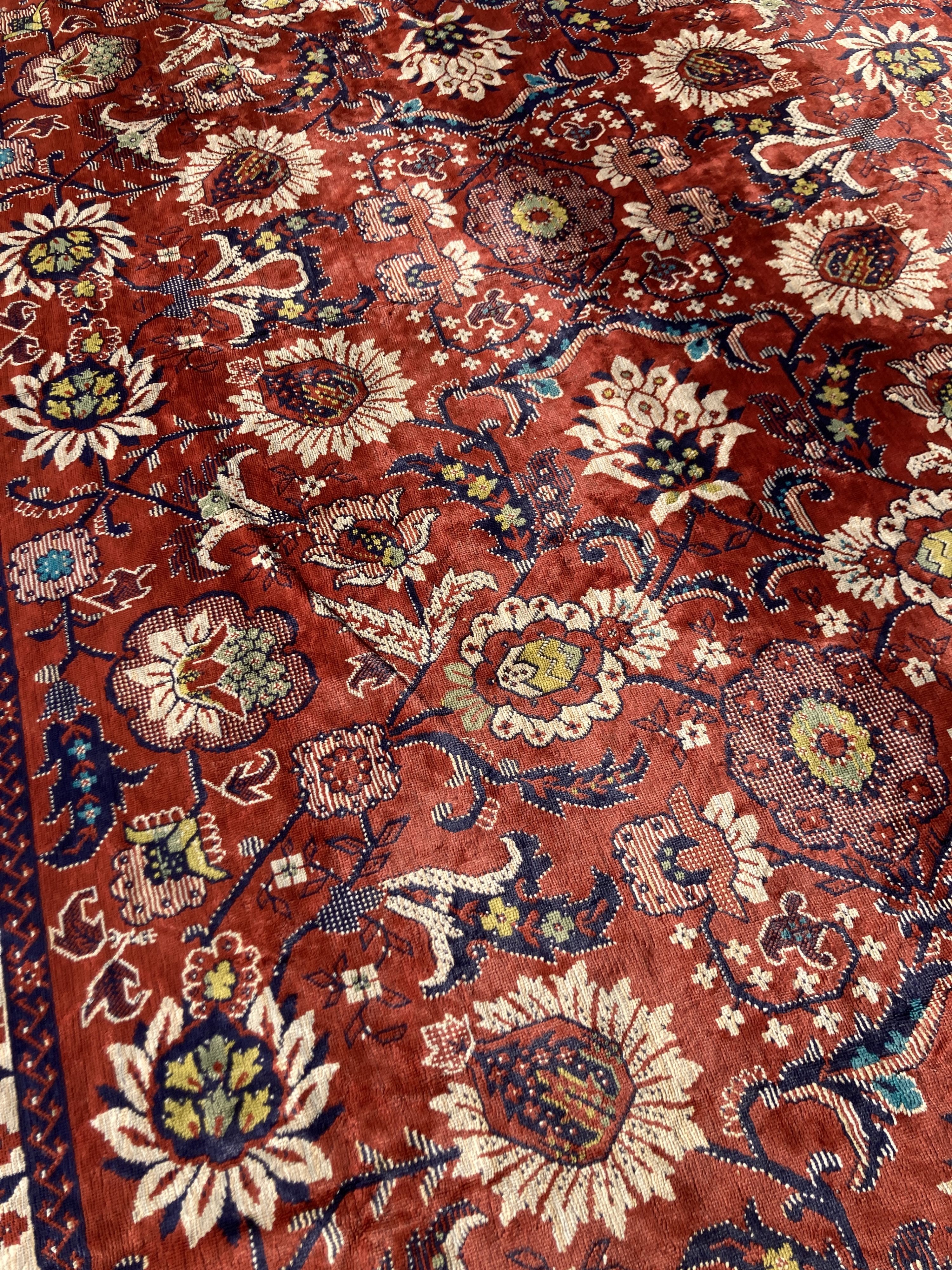 A large embroidered silk rug with a claret red ground interspersed with symmetrical foliate decoration, 136 x 260cm